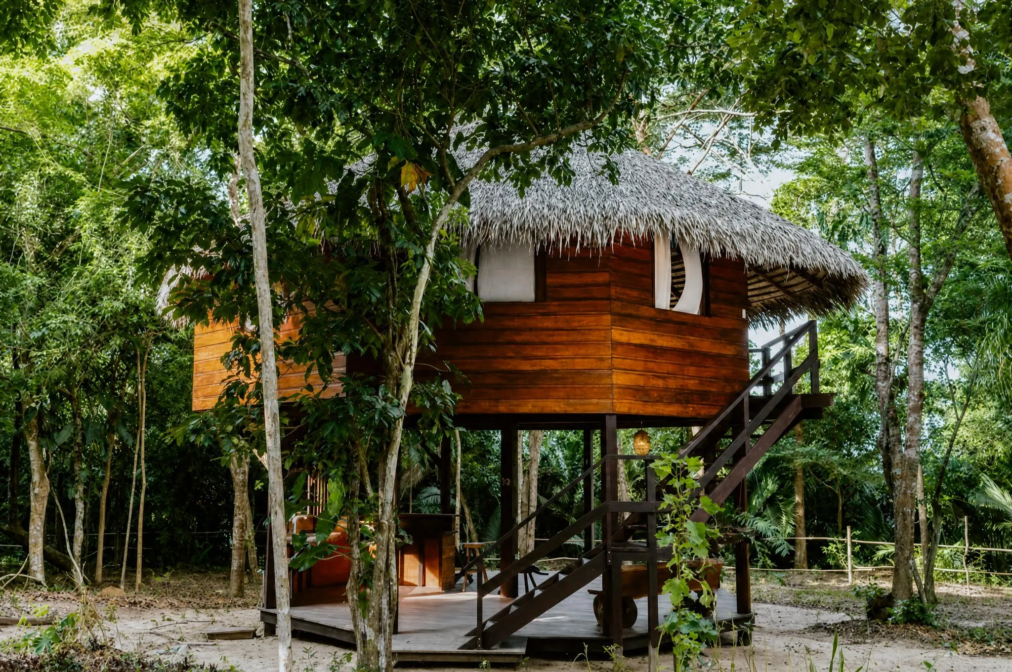 A two-storey timber bungalow on stilts, with a thatched roof
